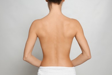 Back view of woman with perfect smooth skin on light grey background, closeup. Beauty and body care