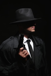 Old fashioned detective with gun on dark background