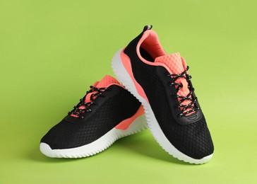 Pair of comfortable sports shoes on light green background