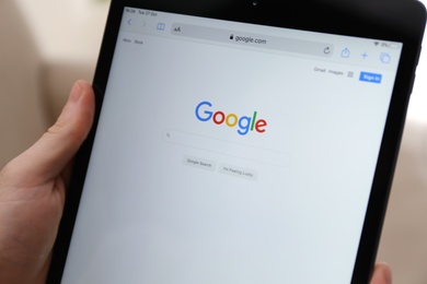 MYKOLAIV, UKRAINE - OCTOBER 27, 2020: Man using Google search engine on tablet against blurred background, closeup