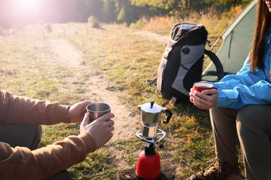 Young couple drinking coffee near camping tents outdoors, closeup