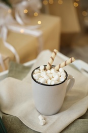 Cup of cocoa with wafer tubes on table indoors. Christmas celebration