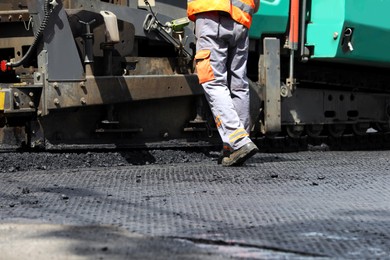 Worker laying new asphalt with paver, closeup. Road repair