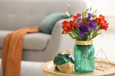 Glass vase with fresh flowers on table in living room. Space for text