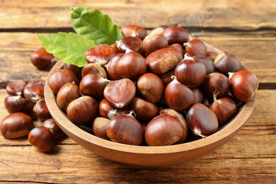 Fresh sweet edible chestnuts in bowl on wooden table