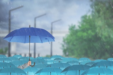 Person holding umbrella over other under heavy rain outdoors 
