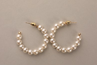 Photo of Elegant earrings with pearls on beige background, top view