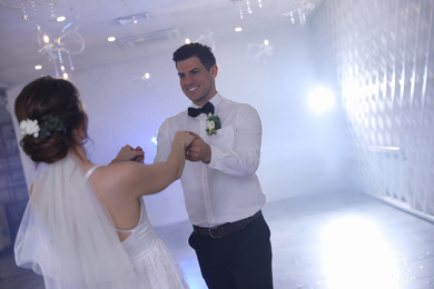 Happy newlywed couple dancing together in festive hall