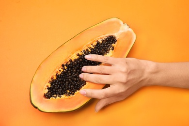Young woman touching half of papaya on orange background, top view. Sex concept