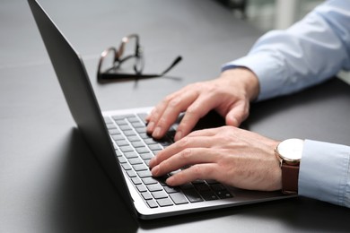 Photo of Man working on laptop at black desk in office, closeup