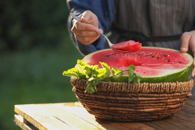 Woman holding spoon of delicious ripe watermelon outdoors, closeup. Space for text