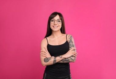 Photo of Woman with tattoos on arms against pink background