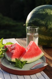 Slices of tasty ripe watermelon on wooden table outdoors