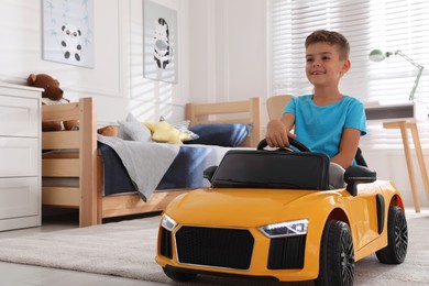Cute little boy driving big toy car at home