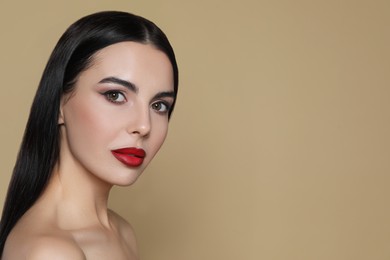 Portrait of young woman wearing beautiful red lipstick on beige background, space for text