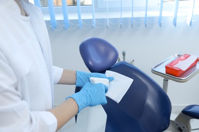 Professional dentist in white coat cleaning workplace  with antiseptic indoors, closeup
