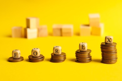Word Forex made of wooden cubes with letters on stacked coins against yellow background