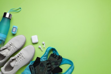 Flat lay composition with different cycling accessories and clothes on green background, space for text
