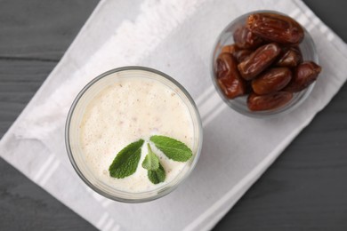 Photo of Glass of delicious date smoothie with mint and dried fruits on grey wooden table, flat lay