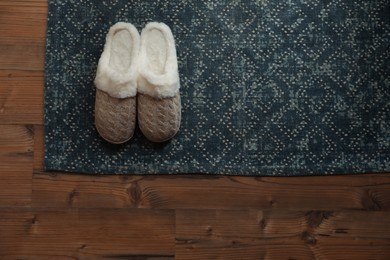 Stylish door mat and slippers on wooden floor, top view. Space for text