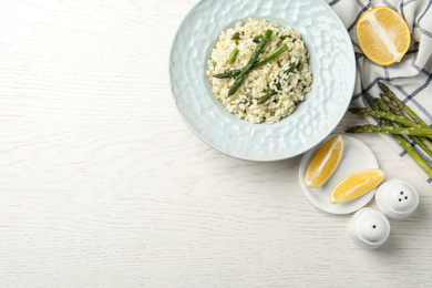 Delicious risotto with asparagus on white wooden table, flat lay. Space for text