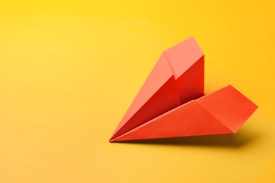 Photo of Handmade orange paper plane on yellow background, space for text