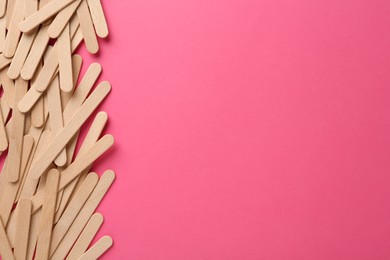 Wooden waxing spatulas on bright pink background, flat lay. Space for text