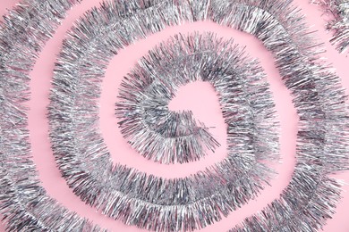 Spiral of silver tinsel on pink background, top view