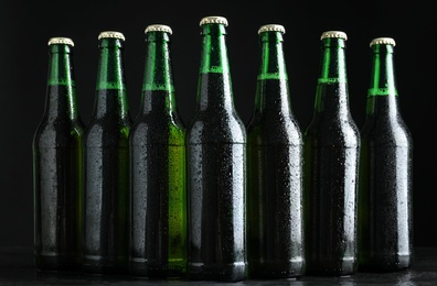 Photo of Glass bottles of beer on table against black background