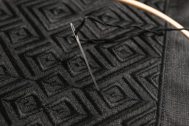 Needle with thread in black shirt, closeup. Ukrainian national clothes