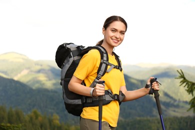 Woman with backpack and trekking poles hiking in mountains