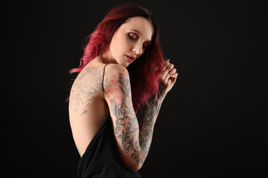Beautiful woman with tattoos on body against black background