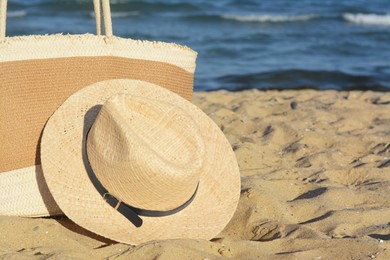 Stylish bag and hat near sea on sunny day, space for text. Beach accessories