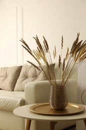 Fluffy reed plumes on table in living room interior