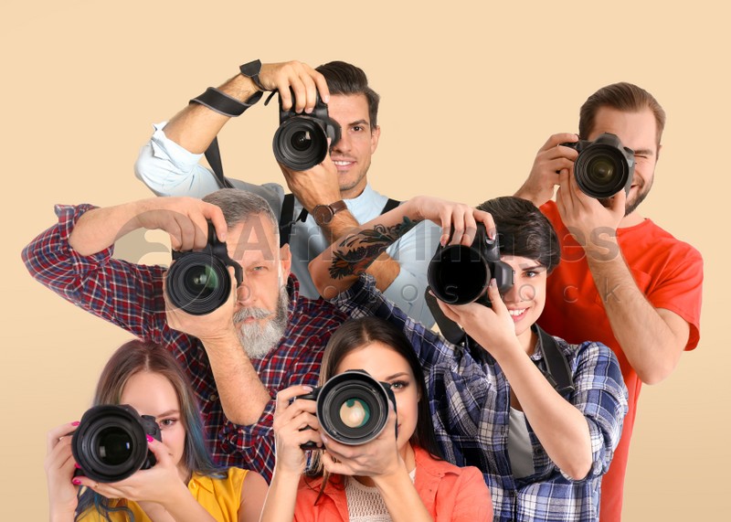 Group of professional photographers with cameras on beige background