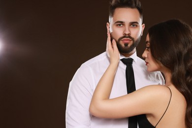 Handsome bearded man with sexy lady on dark brown background