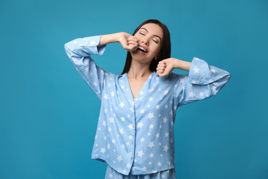 Beautiful Asian woman in pajamas stretching on blue background. Bedtime