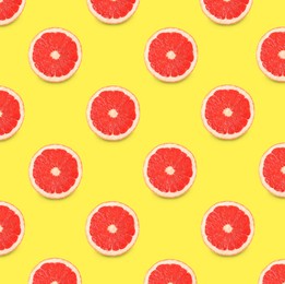 Many fresh ripe slices of grapefruits on yellow background, flat lay. Seamless pattern design