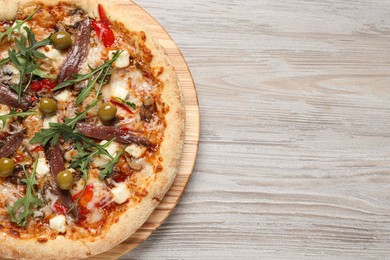 Photo of Tasty pizza with anchovies, arugula and olives on grey wooden table, top view. Space for text