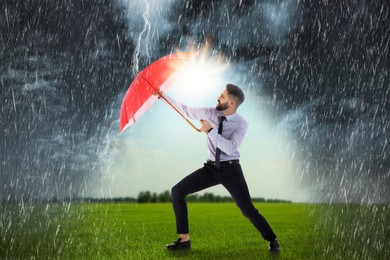 Businessman with umbrella under heavy rain. Insurance concept