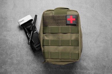 Photo of Military first aid kit and tourniquet on light grey table, flat lay