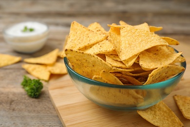 Bowl of Mexican nacho chips on wooden table, closeup