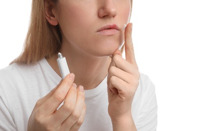 Woman with herpes applying cream on lips against white background, closeup