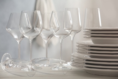 Set of clean dishware and wineglasses on white table indoors