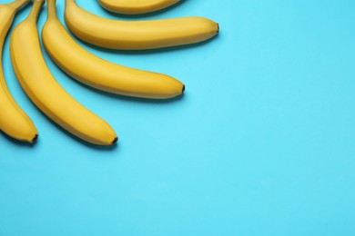 Ripe yellow bananas on turquoise background, flat lay. Space for text