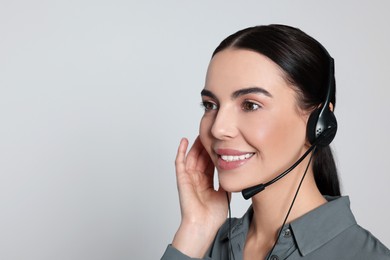 Photo of Hotline operator with modern headset on light grey background, space for text. Customer support