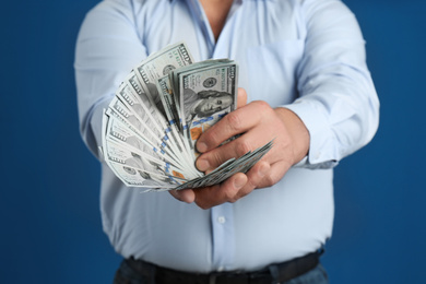 Senior man with cash money on blue background, closeup