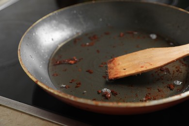 Frying pan with spatula and used cooking oil on stove, closeup