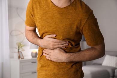 Young man suffering from stomach ache at home, closeup. Food poisoning