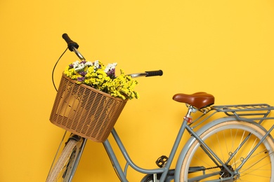 Retro bicycle with wicker basket on color background